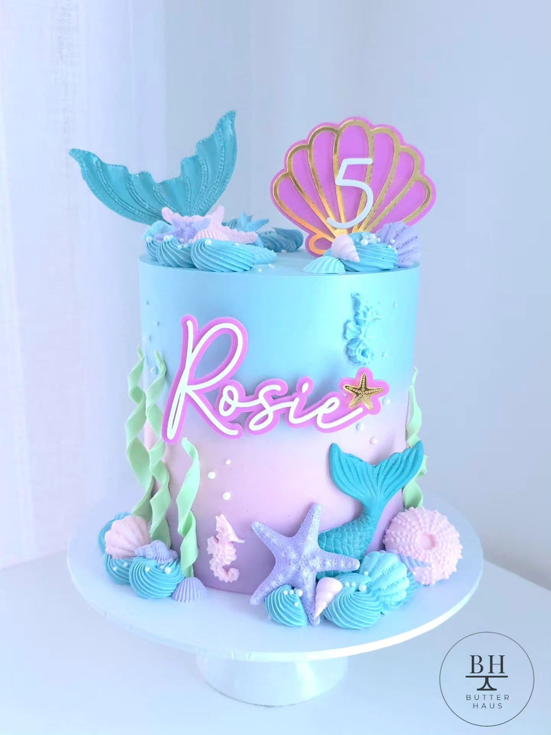 Blue to pink ombre mermaid cake with mermaid tail, seashell age topper and sea details