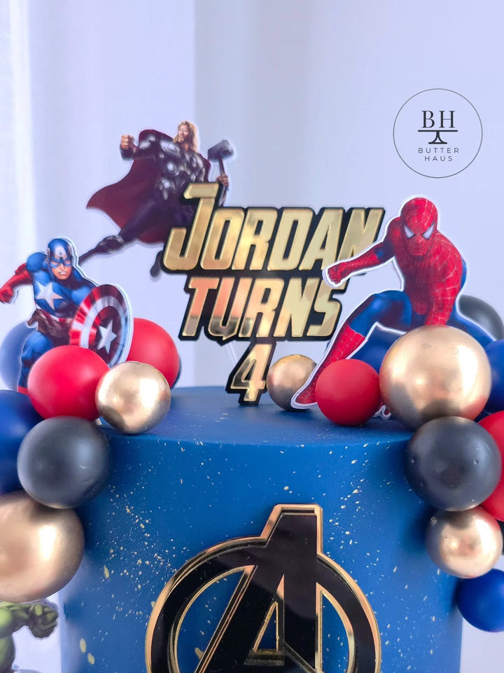 Avengers birthday cake with Hulk and Iron Man cardstock cutouts on gold-speckled galaxy-effect buttercream