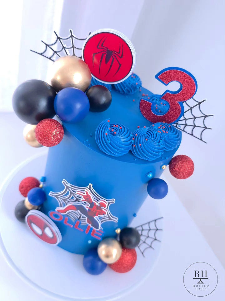 Spiderman birthday cake with red age number topper and spiderweb decorations