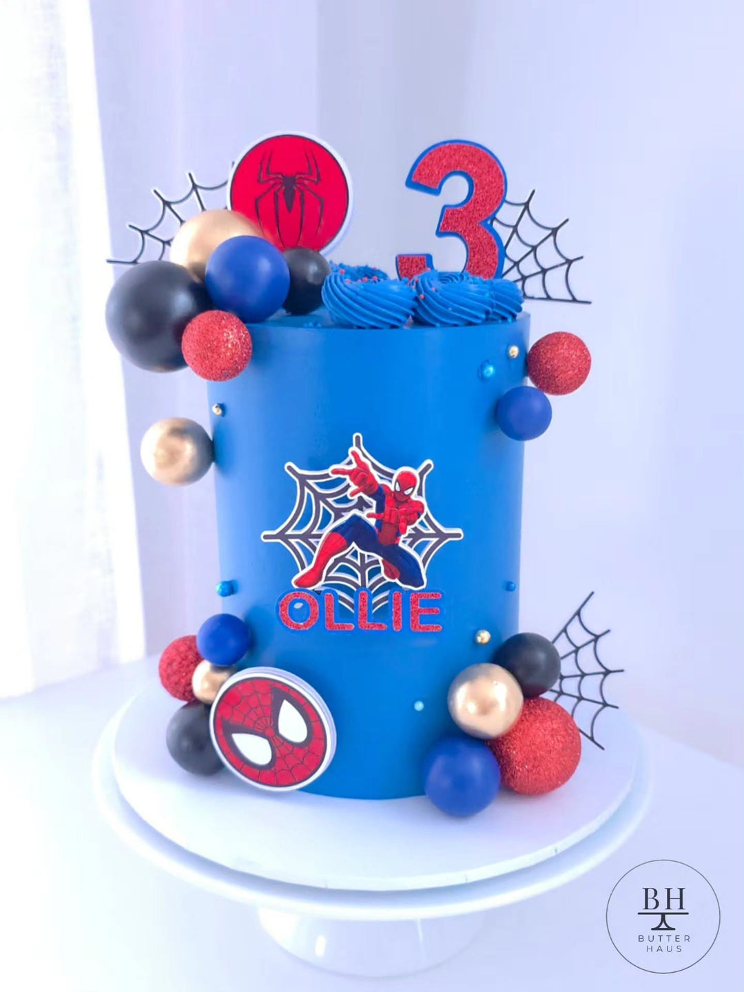 Spiderman Party birthday cake in blue buttercream with Spiderman cardstock image, spiderweb toppers and red, blue, black and gold balls