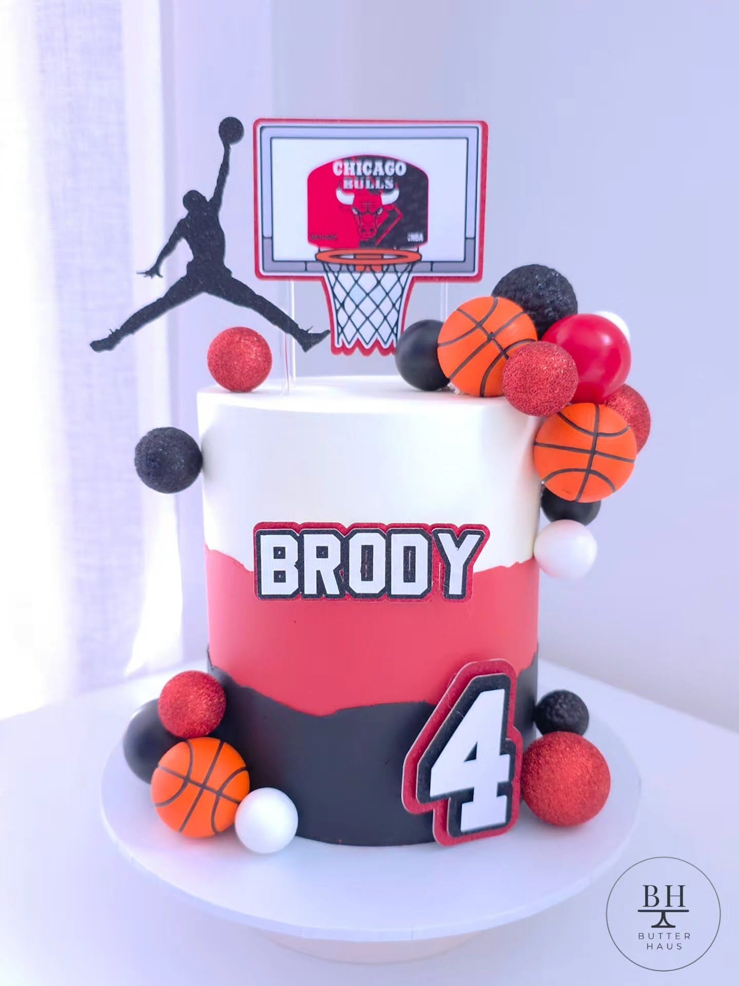 Close-up of the basketball birthday cake showing a glitter ball, mini basketball topper and team colour detail