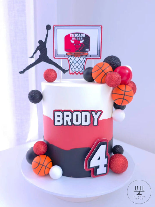 Close-up of the basketball birthday cake showing a glitter ball, mini basketball topper and team colour detail