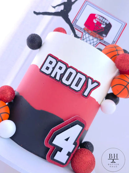 Full front view of the basketball birthday cake with jump-shot silhouette topper, scoreboard-style hoop topper, custom name plaque and number topper