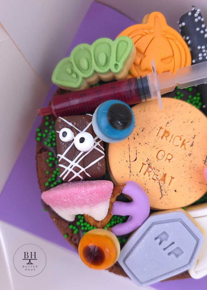 Halloween brownie with red blood drizzle syringe and Trick or Treat iced cookie