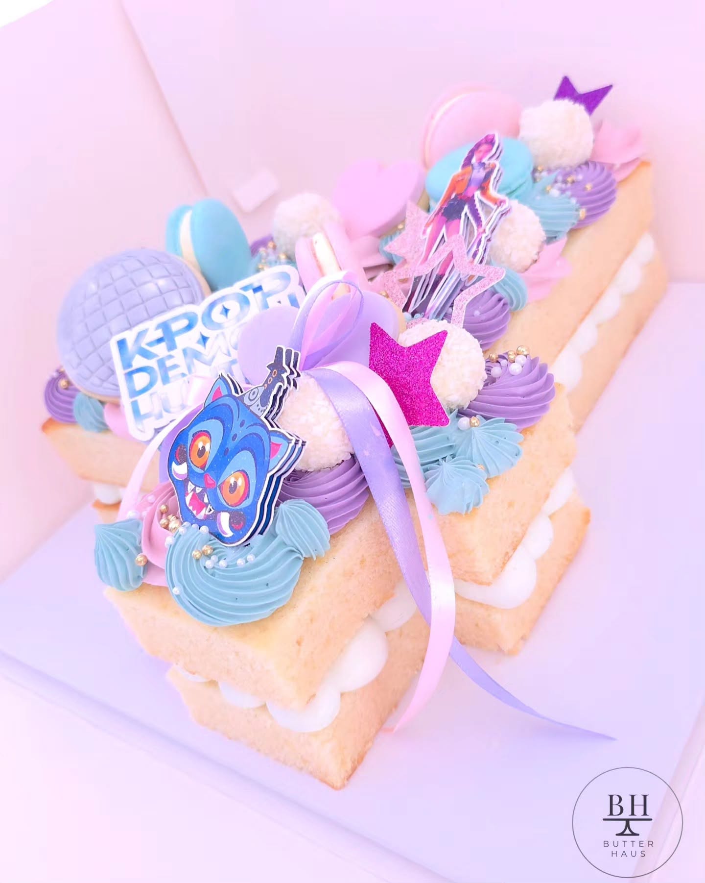 Close-up of the K-pop demon hunter number cake showing macarons, chocolates and the double-layered bow detail