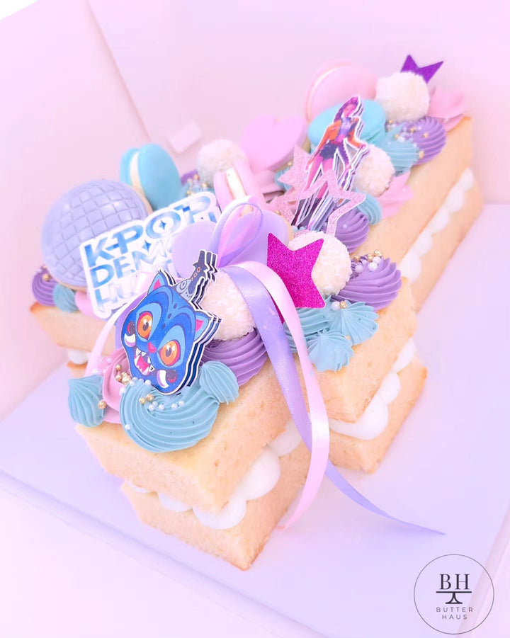 Close-up of the K-pop demon hunter number cake showing macarons, chocolates and the double-layered bow detail