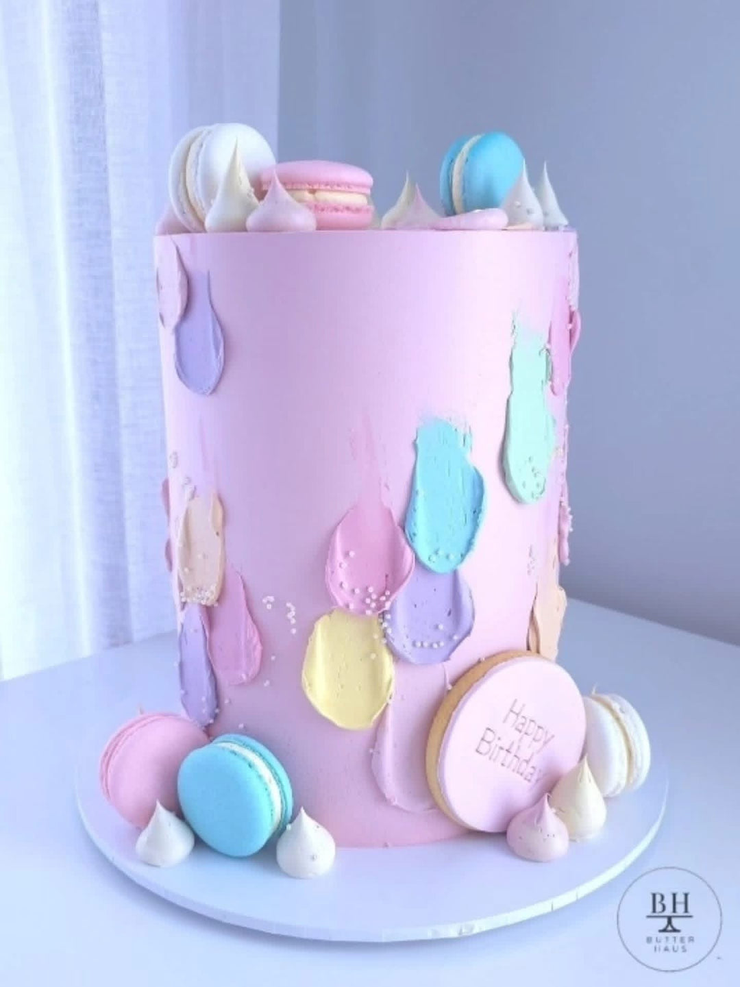 Pink birthday cake with pastel brushstrokes, macarons, meringue kisses and Happy Birthday plaque