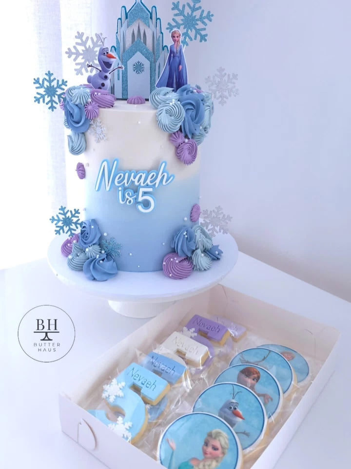 Icy blue birthday cake with ice castle, Elsa and Olaf inspired toppers and snowflakes