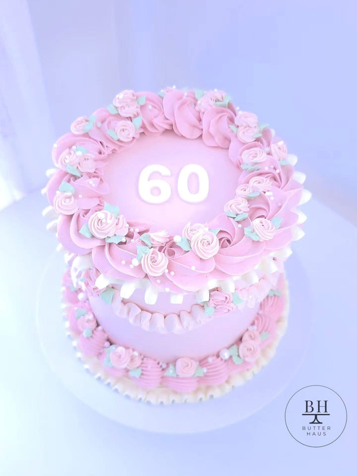 Pink vintage birthday cake with piped roses, mint leaves, ruffles, pearl sprinkles and number topper