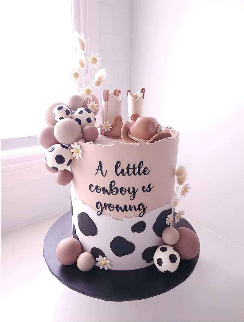 Little Rodeo western birthday cake with cow-print accents and handmade fondant cowboy hat and boots