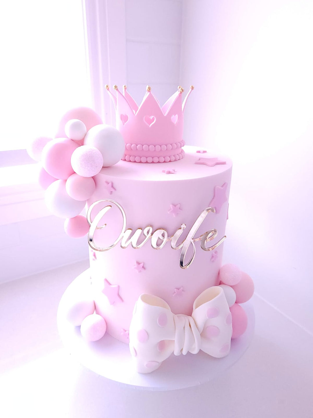 Once Upon A Bow birthday cake with pastel buttercream, statement crown topper and fondant bow detail