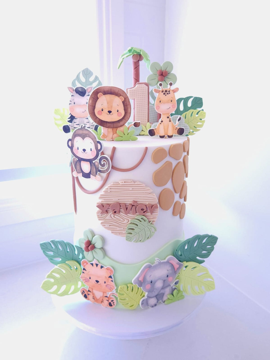 Little Wild One jungle birthday cake with neutral buttercream, fondant leaves and cardstock safari animals