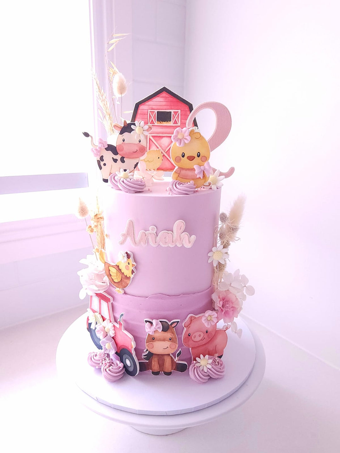 Side view of Little Farm Friends cake with custom name and age topper