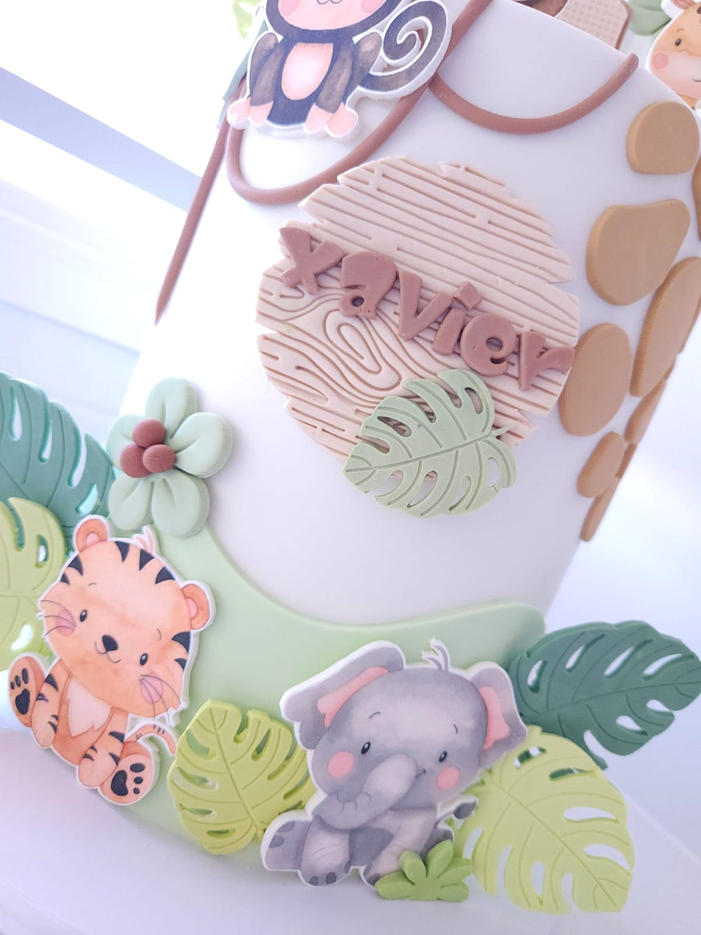 Close-up of fondant leaves and safari animal cutouts on Little Wild One cake