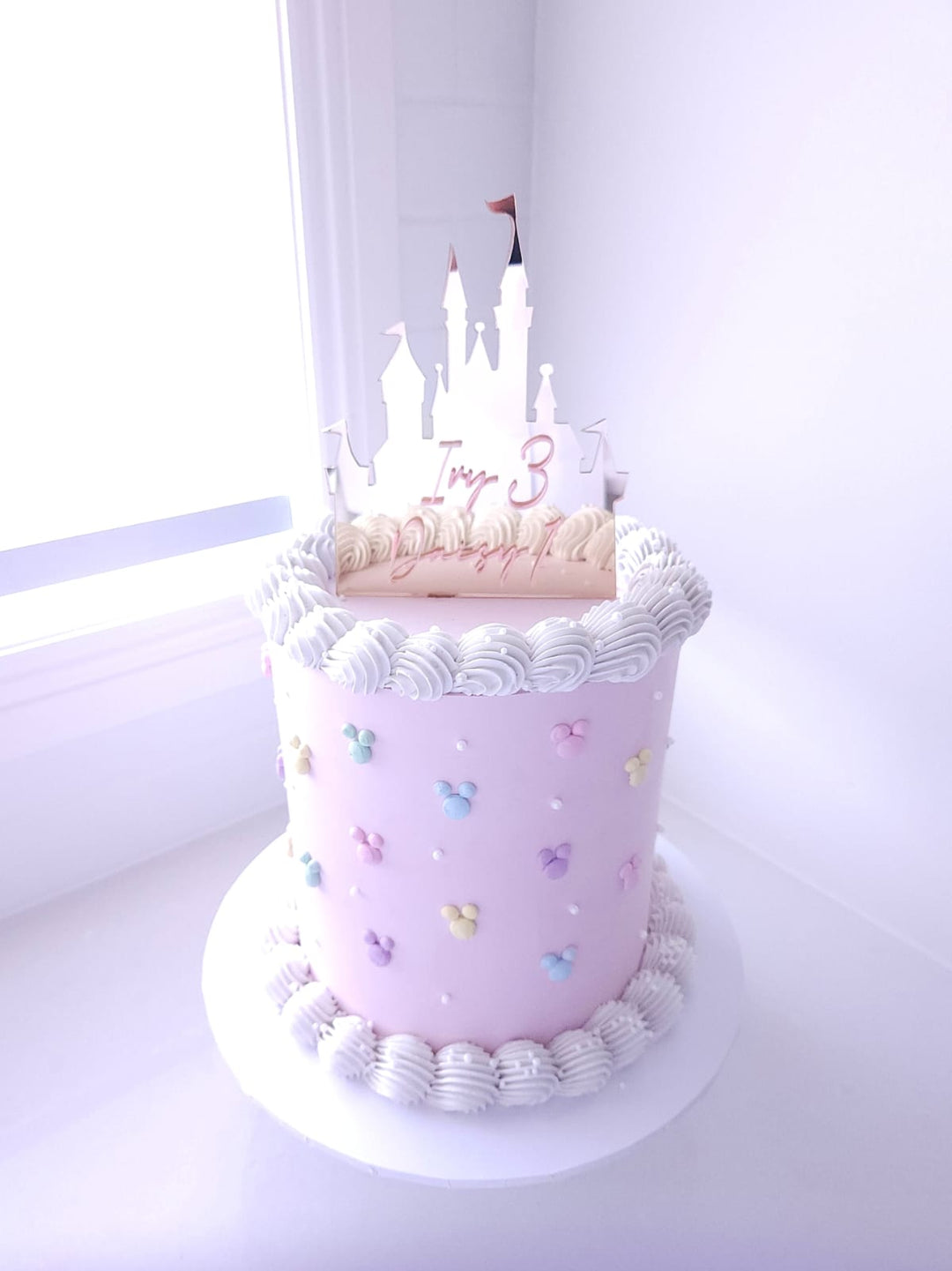Once Upon a Castle birthday cake with pastel buttercream, piped borders and acrylic castle topper