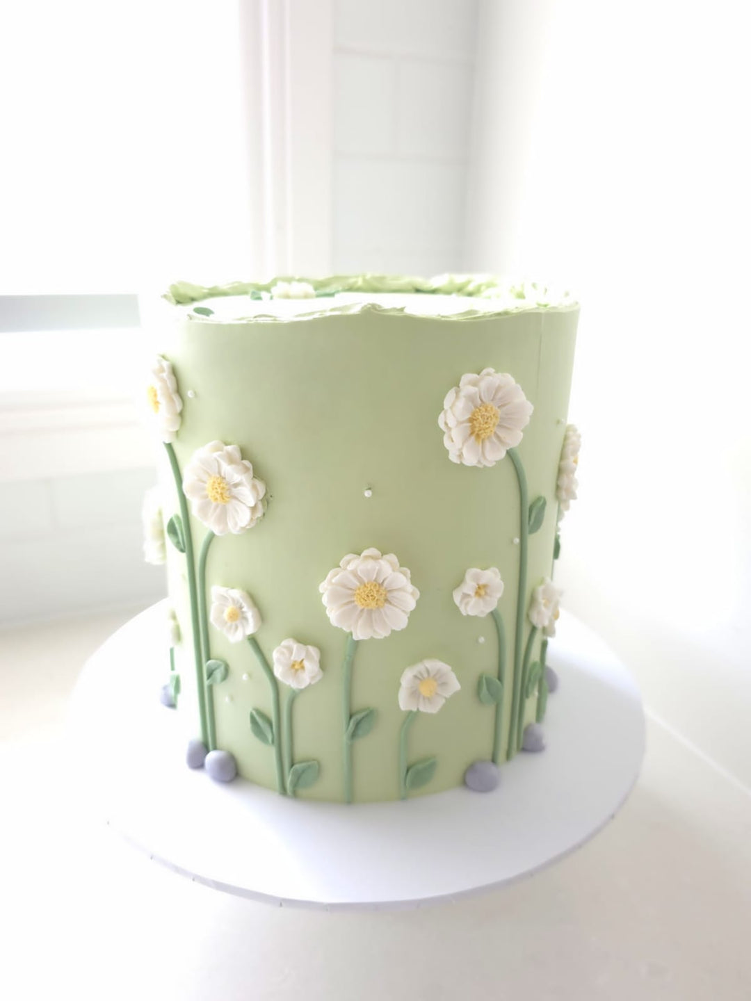 Sweet Meadow soft green buttercream birthday cake with hand-piped white florals and yellow centres