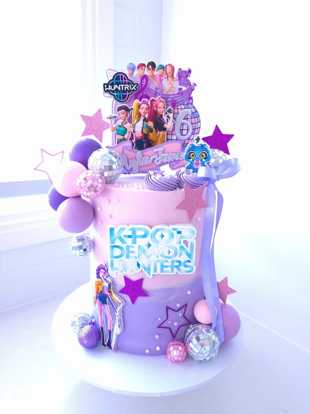K-Pop Demon Hunters ombre buttercream birthday cake with silver and purple disco balls and characters
