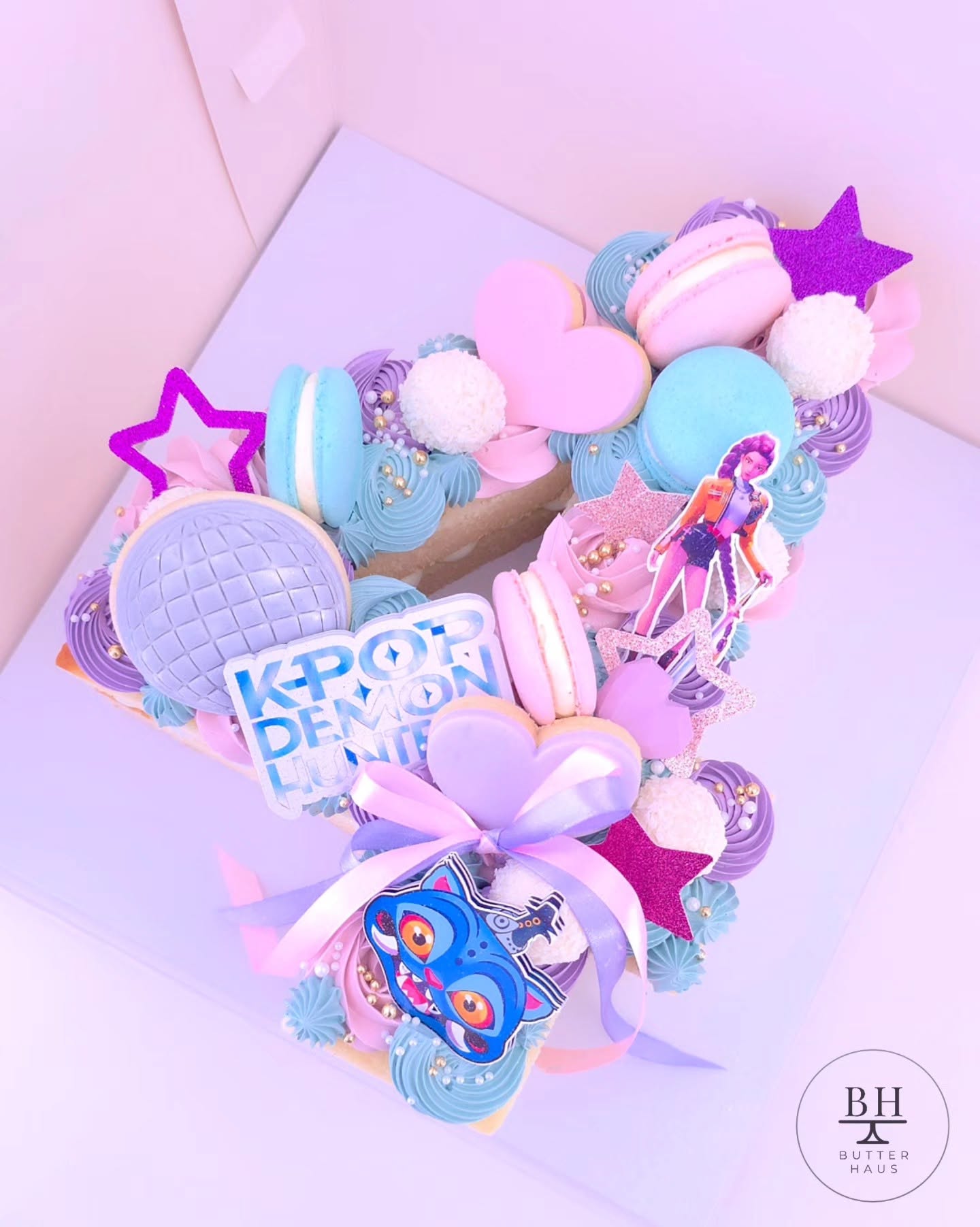 K-pop demon hunter inspired number cake with cardstock character art, disco ball cookie, macarons and glitter stars