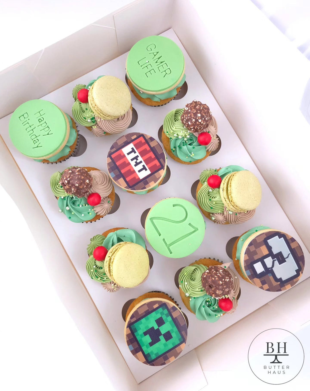 Box of green and brown cupcakes with Minecraft inspired pixel discs and green macarons