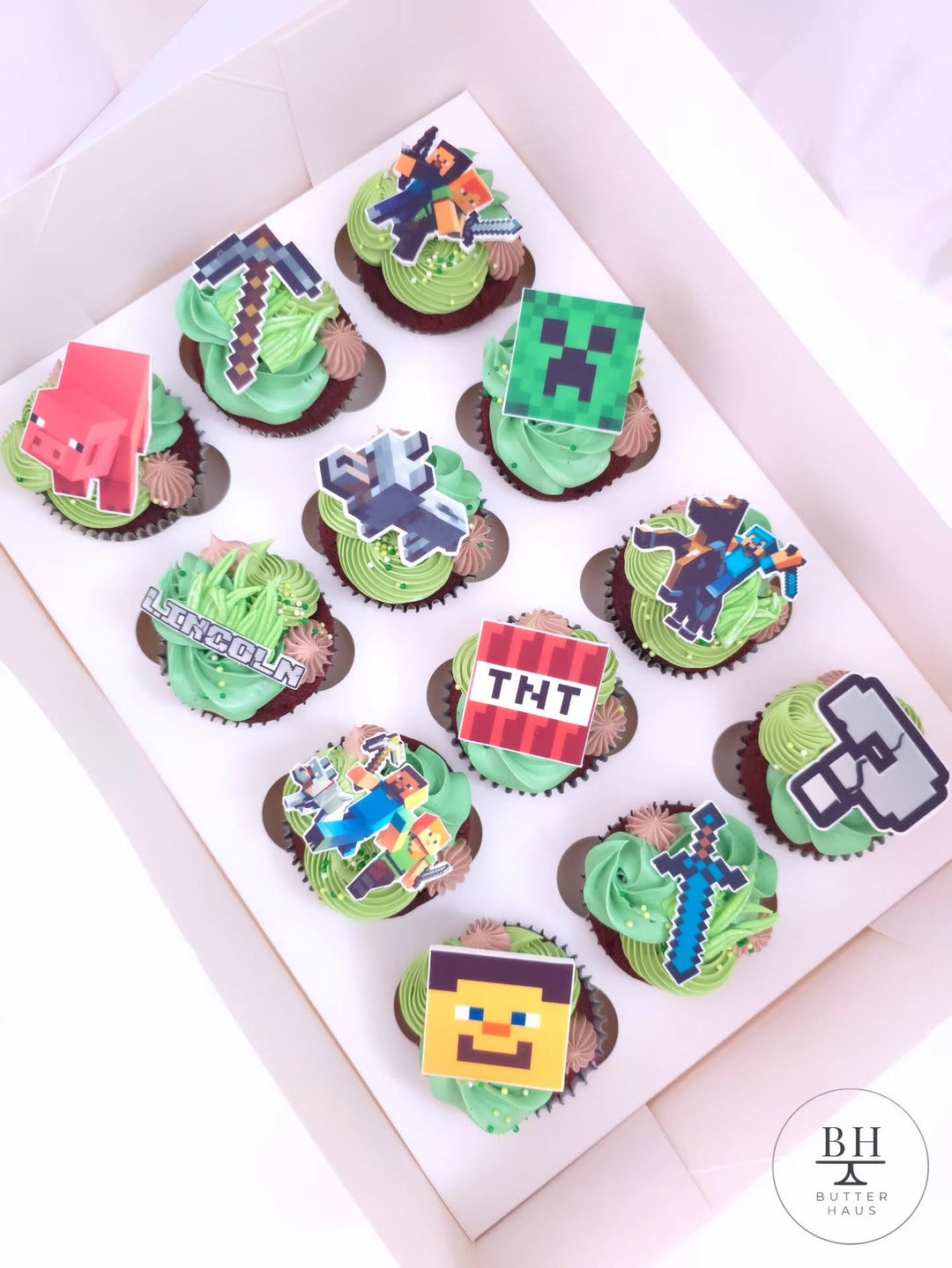 Box of grass green cupcakes with Minecraft inspired pixel toppers and chocolate accents