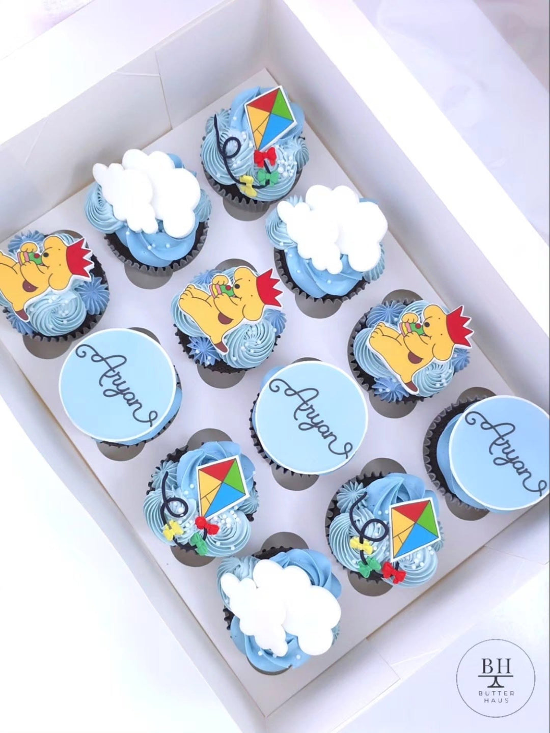 Box of blue cupcakes with fondant kites, clouds and Spot the dog inspired toppers